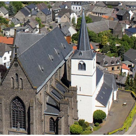 Eine Doppelkirche, die linke größer und aus Basaltstein, die rechte kleiner und weiß